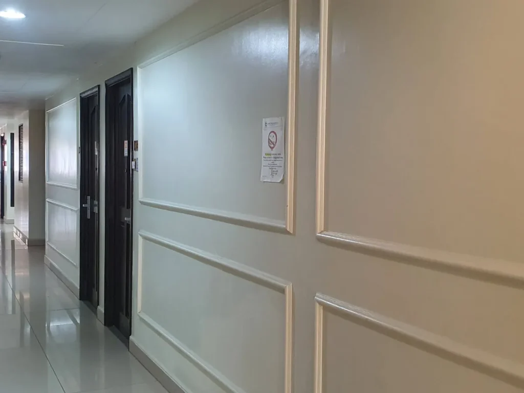 필리핀 세부 블루오션(BLUEOCEAN) 어학원 내부 기숙사 복도로 짙은 우드 객실 문과 몰딩 벽면이 이어진 통로 측면입니다