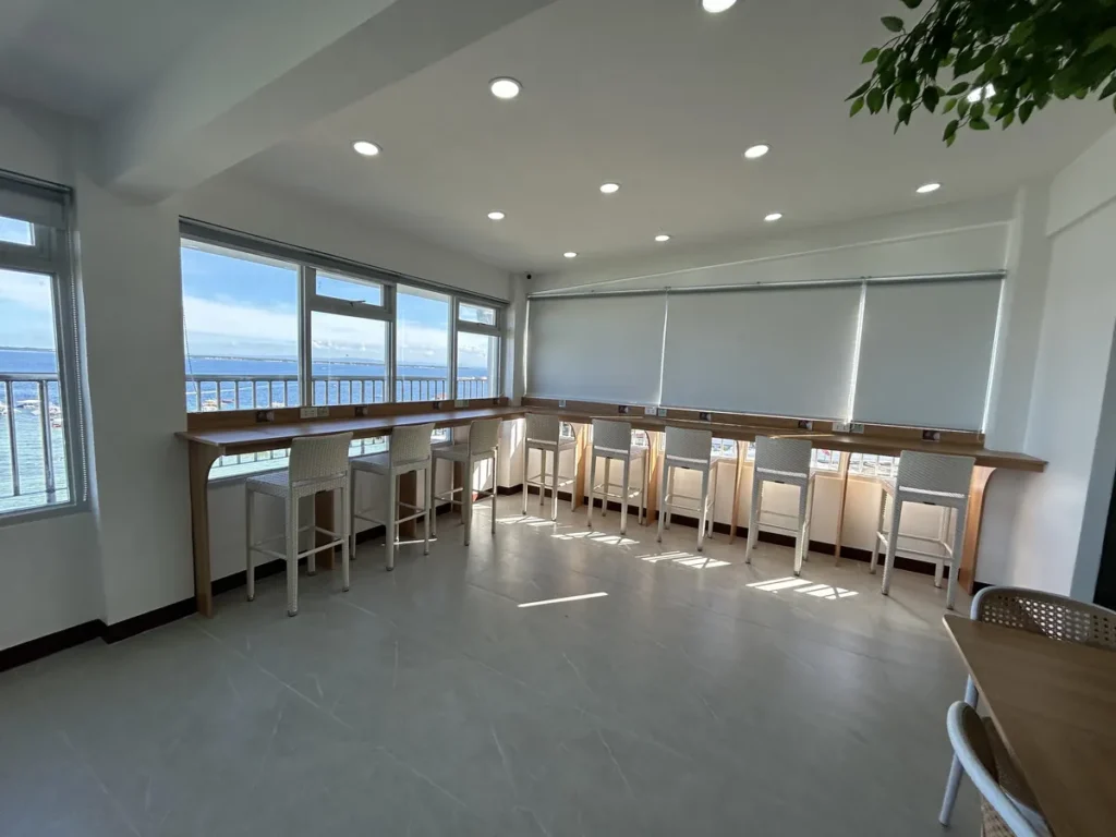 필리핀 세부 블루오션(BLUEOCEAN) 어학원 부대시설 라운지로 인조나무 아래 대형 테이블과 파란 1인 소파가 놓인 휴식 공간입니다