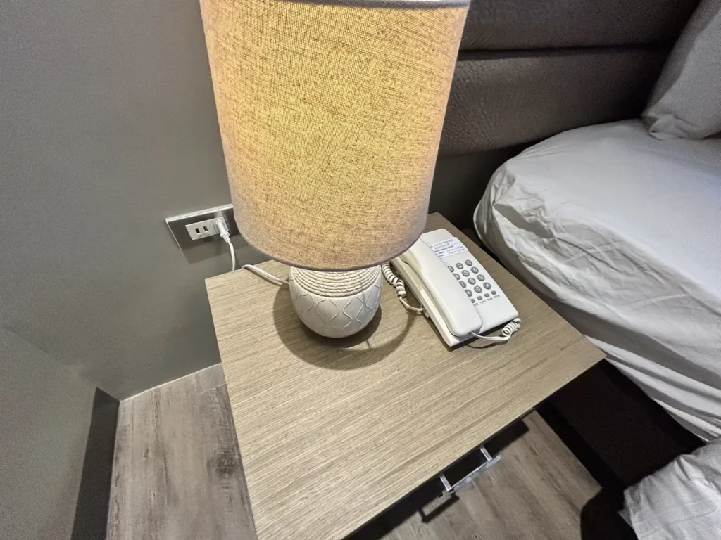 필리핀 세부 블루오션(BLUEOCEAN) 어학원 외부숙소 1인실 디럭스 객실 침대 옆 협탁의 스탠드 조명과 전화기