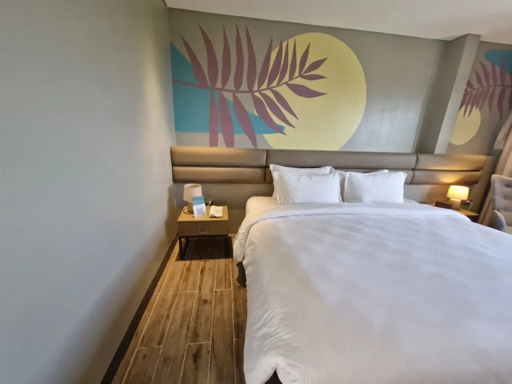 필리핀 세부 블루오션(BLUEOCEAN) 어학원 외부기숙사 객실의 야자수 벽화 헤드보드와 흰 침구의 침대