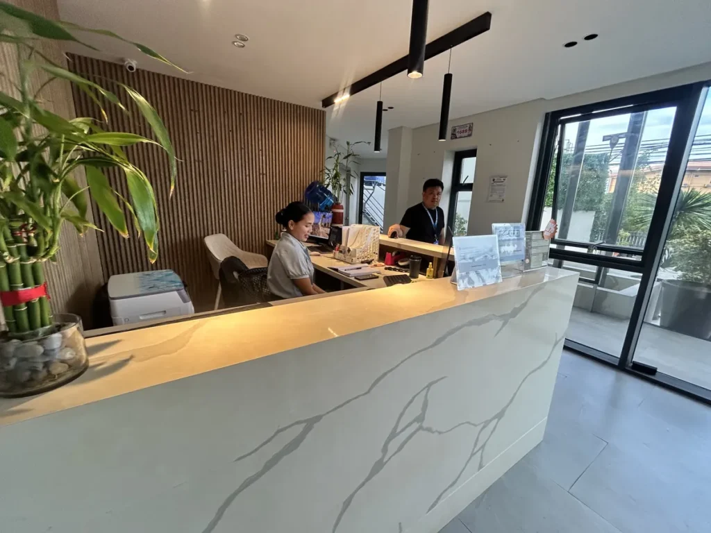 필리핀 세부 블루오션(BLUEOCEAN) 어학원 외부숙소 로비, 대리석 카운터의 리셉션 데스크와 직원 모습