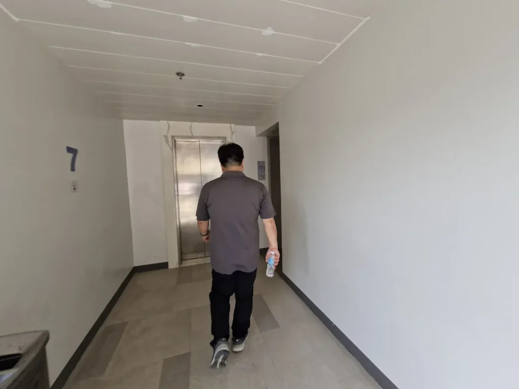 필리핀 세부 블루오션(BLUEOCEAN) 어학원 외부숙소 7층 엘리베이터 앞 복도로, 한 사람이 엘리베이터로 향하고 있습니다.