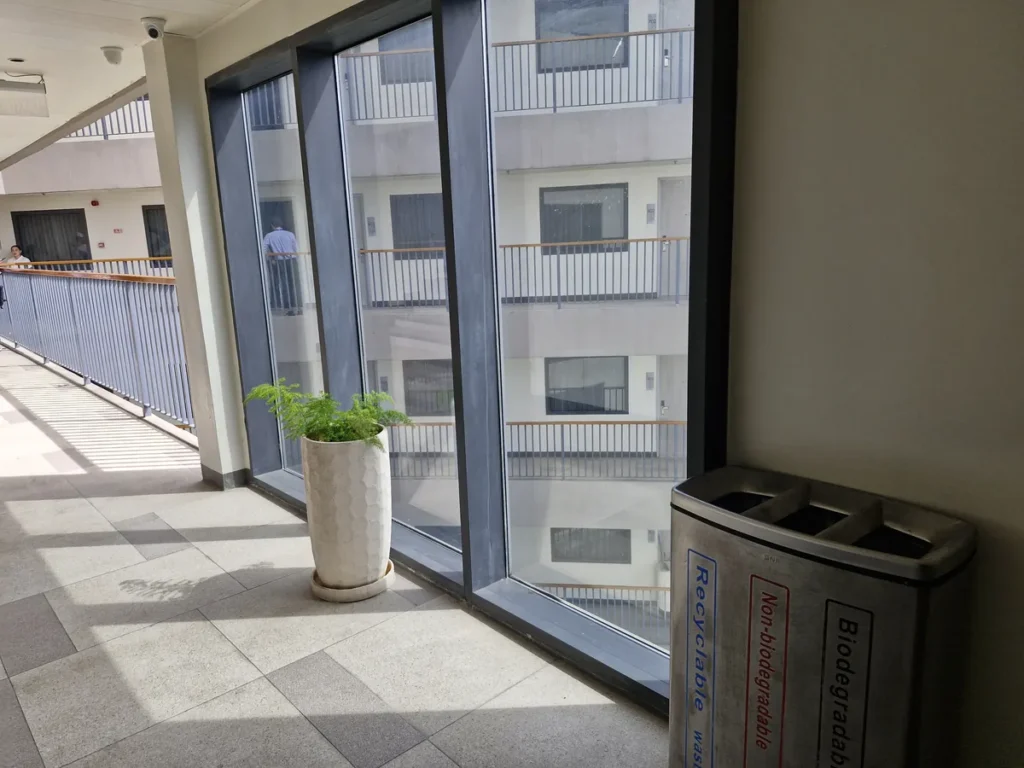 필리핀 세부 블루오션(BLUEOCEAN) 어학원 외부숙소 복도로, 통유리 벽 옆에 화분과 분리수거함이 놓여 있습니다.