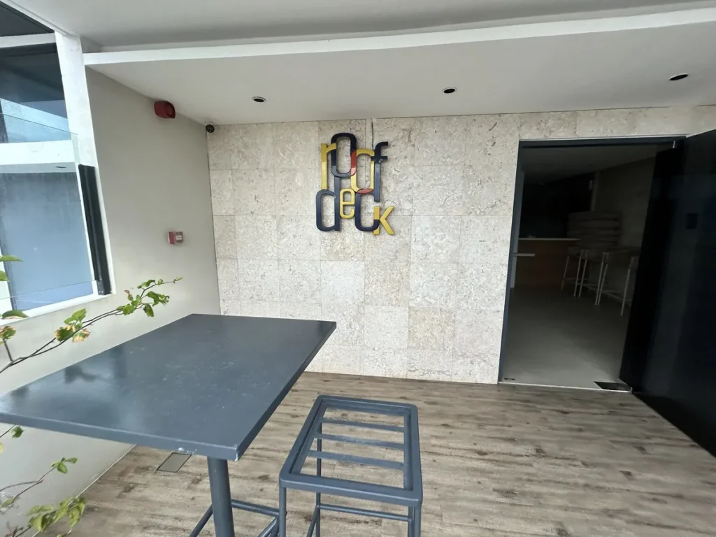필리핀 세부 블루오션(BLUEOCEAN) 어학원 외부숙소 옥상 루프덱 입구로, roof deck 사인이 붙은 석재 벽과 입식 테이블입니다.