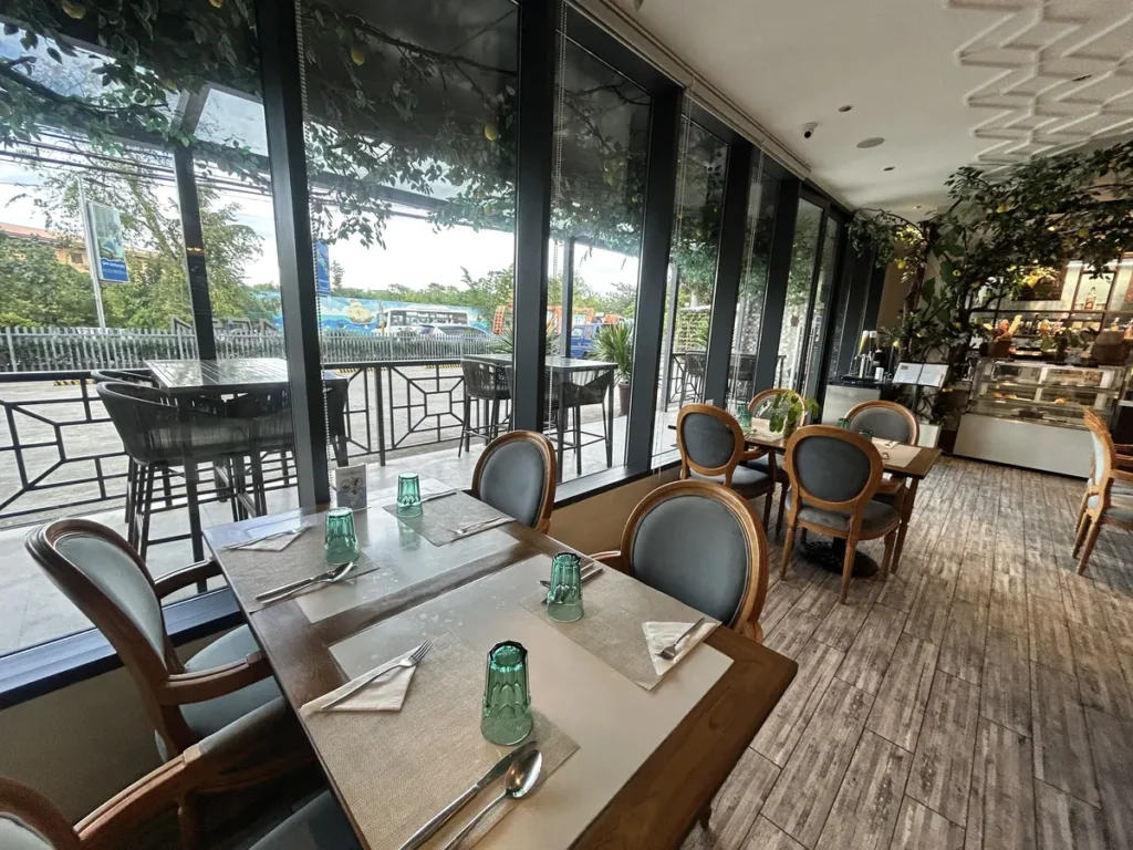 필리핀 세부 블루오션(BLUEOCEAN) 어학원 외부숙소 부대시설로, 통유리창과 야외 발코니를 끼고 식기가 놓인 레스토랑 테이블석입니다.