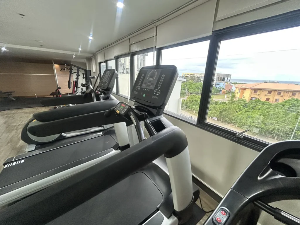 필리핀 세부 블루오션(BLUEOCEAN) 어학원 외부숙소 운동시설로 유리문에 GYM 표시가 붙은 입구 너머로 운동 기구가 보이는 헬스장입니다