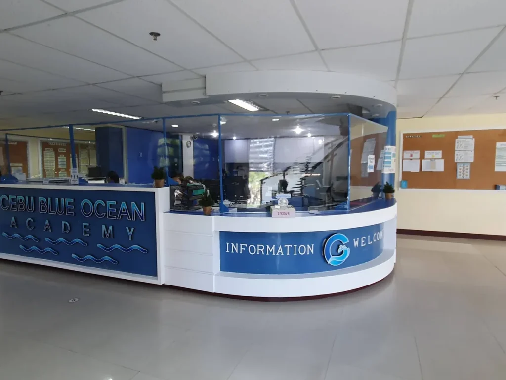 필리핀 세부 블루오션(BLUEOCEAN) 어학원 입구홀의 CEBU BLUE OCEAN ACADEMY 로고가 새겨진 곡선형 인포메이션 안내데스크