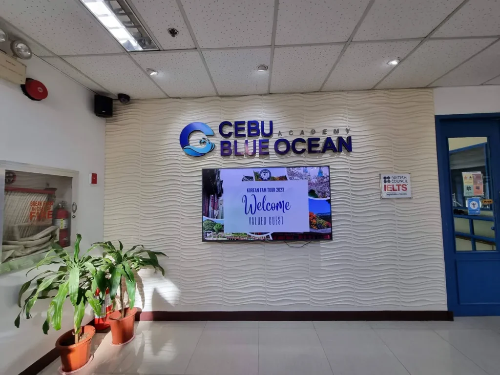필리핀 세부 블루오션(BLUEOCEAN) 어학원 입구홀에서 학생들이 CEBU BLUE OCEAN ACADEMY 인포메이션 데스크 앞에 줄 서 있는 모습