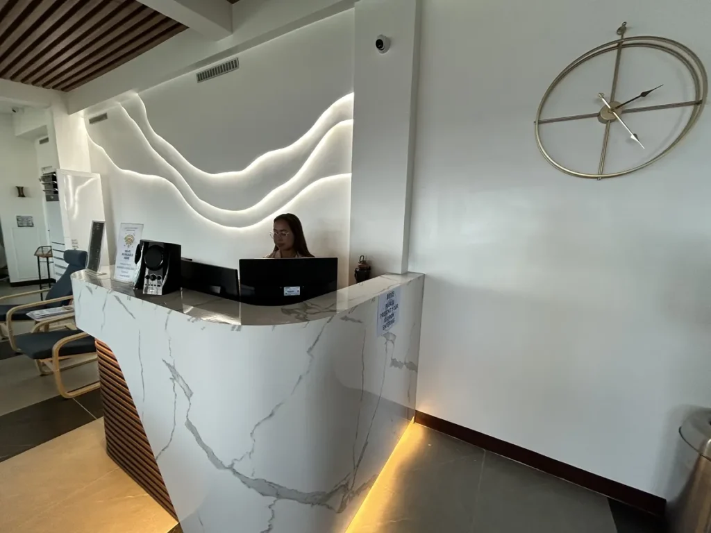 필리핀 세부 블루오션(BLUEOCEAN) 어학원 입구홀의 웨이브 조명 벽면을 배경으로 한 대리석 안내 데스크와 큰 벽시계