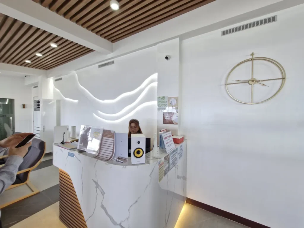 필리핀 세부 블루오션(BLUEOCEAN) 어학원 입구홀의 웨이브 조명 벽면과 대리석 안내 데스크, 원목 천장과 금색 벽시계