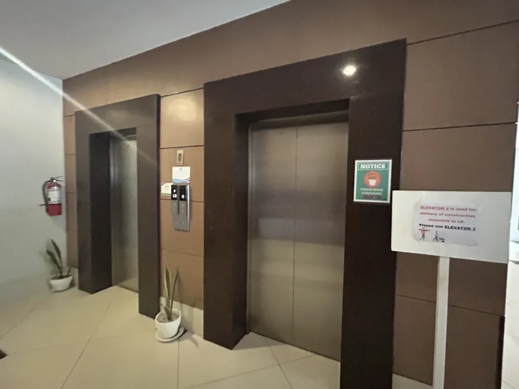 필리핀 세부 블루오션(BLUEOCEAN) 어학원 건물의 엘리베이터홀, 브라운 패널 벽면의 엘리베이터 두 대와 이용 안내문