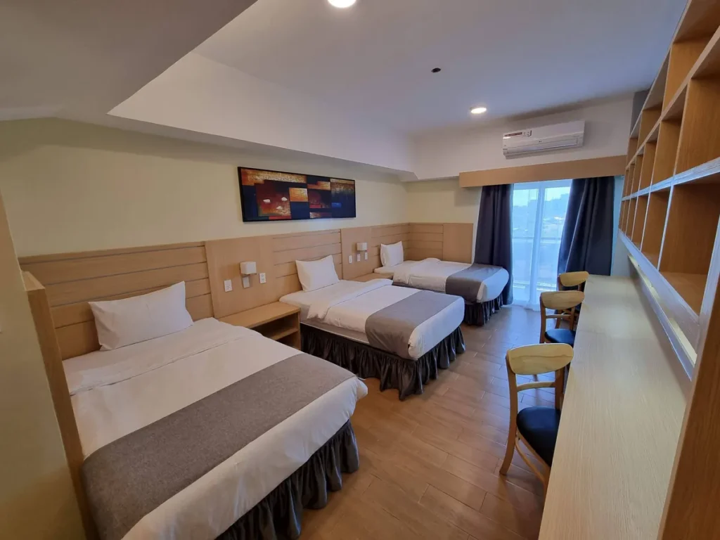 필리핀 세부 CIA어학원 내부기숙사 3인실 전경으로 침대 세 개와 벽면 책장, 발코니가 보입니다.