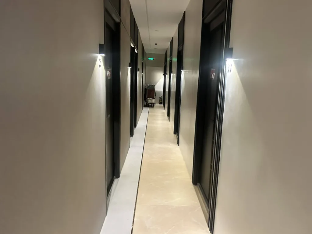 필리핀 세부 CIA어학원 외부 숙소 양옆 객실 문 사이 벽등이 켜진 호텔형 복도 모습