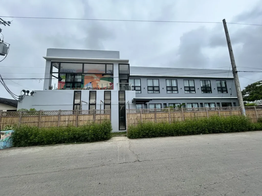 필리핀 세부 CIA어학원 외부기숙사 외관, 통유리 입구를 갖춘 회색 2층 건물과 담장이 정면으로 보이는 전경