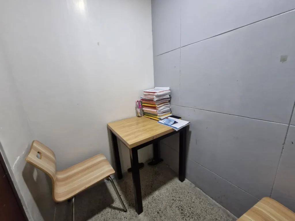 필리핀 세부 CIA어학원 1대1 수업실, 벽 선반과 화이트보드를 갖춘 좁은 부스에 책상과 의자 두 개가 놓여 있습니다.