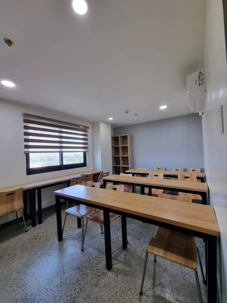 필리핀 세부 CIA어학원 그룹 강의실, 창가 선반 책상과 모서리 책장을 둔 밝은 소그룹 교실입니다.