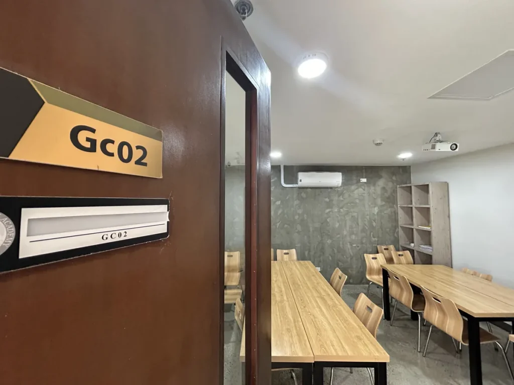 필리핀 세부 CIA어학원 그룹 강의실, Gc02 호실 표지판이 붙은 문 너머로 책상과 의자가 놓인 교실이 보입니다.