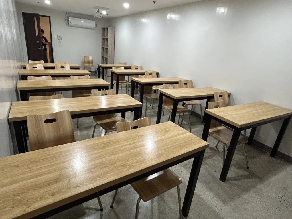 필리핀 세부 CIA어학원 그룹 강의실, 2인용 원목 책상을 여러 줄로 배열한 넓은 강의실 전경입니다.
