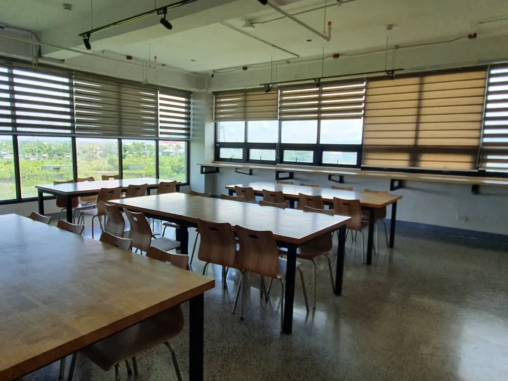 필리핀 세부 CIA어학원 자습실 개인 칸막이 책상이 일렬로 늘어선 모습과 안쪽 책장이 보입니다.