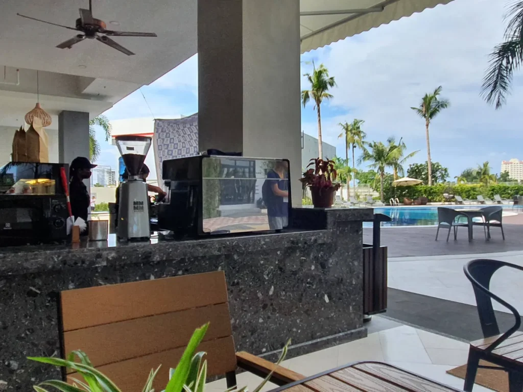 필리핀 세부 CIA어학원 라운지 및 카페, 수영장과 야자수가 보이는 곳에 원목 좌석과 카페 바가 놓인 모습