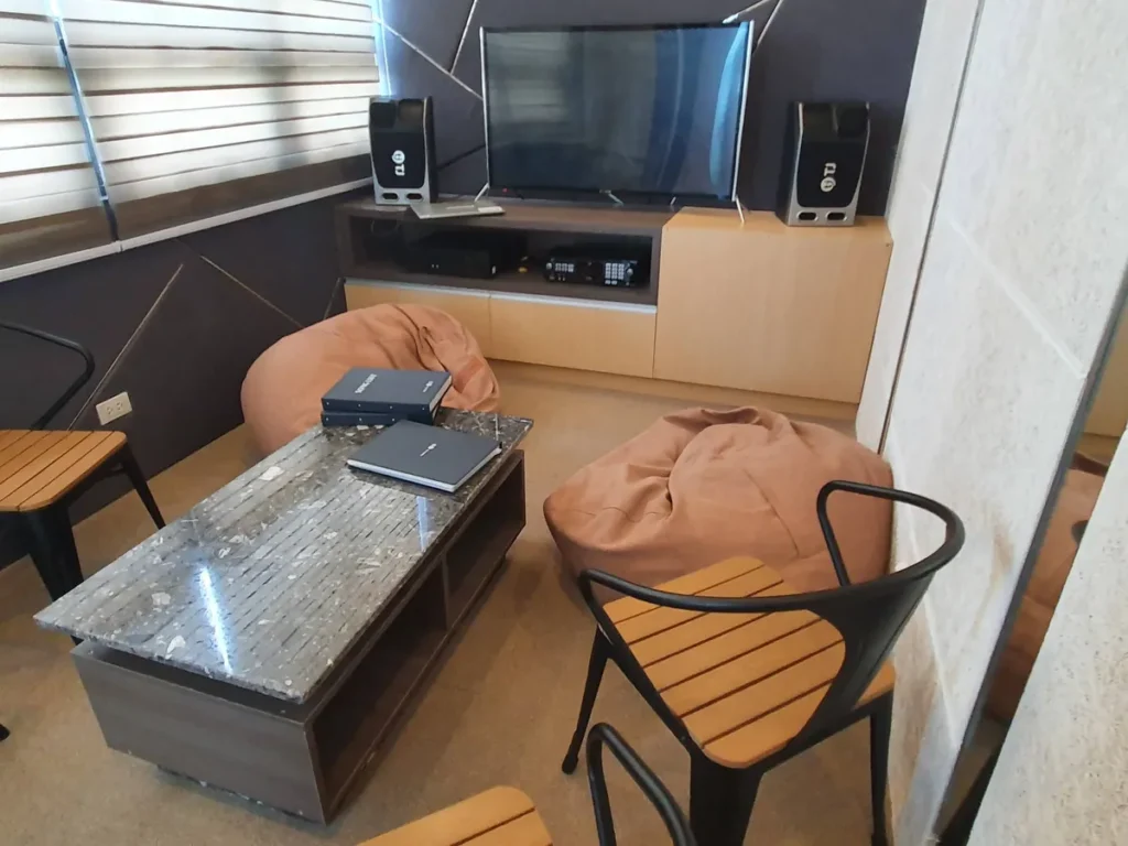 필리핀 세부 CIA어학원 부대시설 노래방 내부, TV와 빈백 소파, 노래책이 놓인 모습