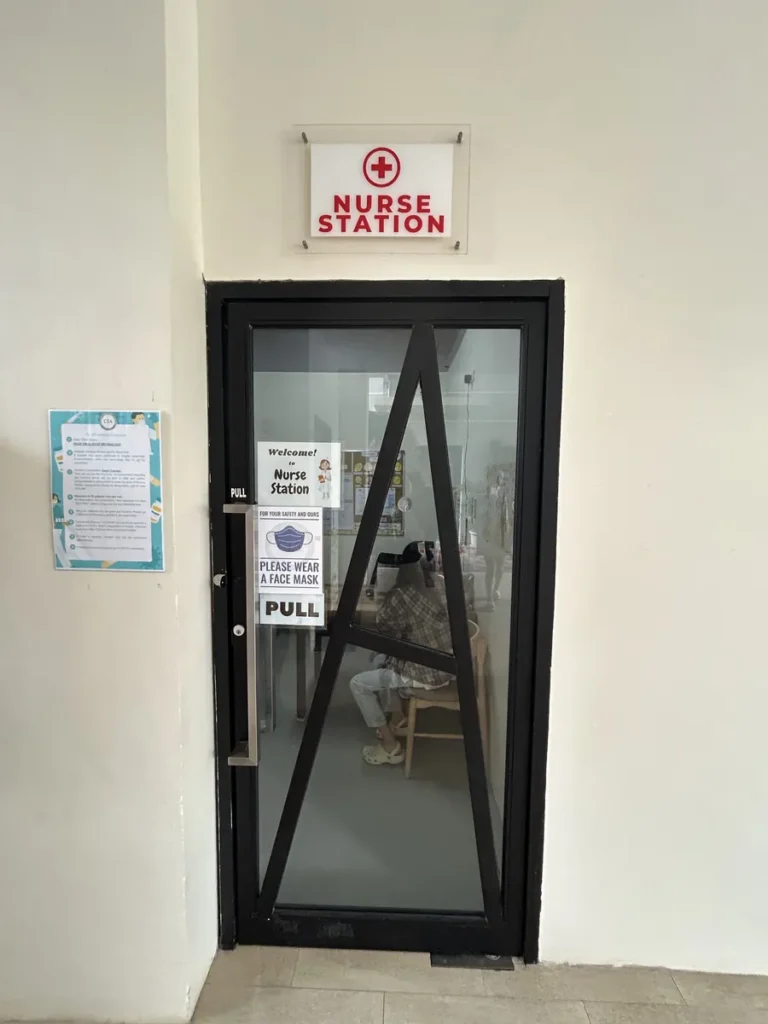 필리핀 세부 CIA어학원 의무실 입구로, 적십자 마크의 NURSE STATION 사인 아래 유리문에 마스크 착용 안내문이 붙어 있습니다.