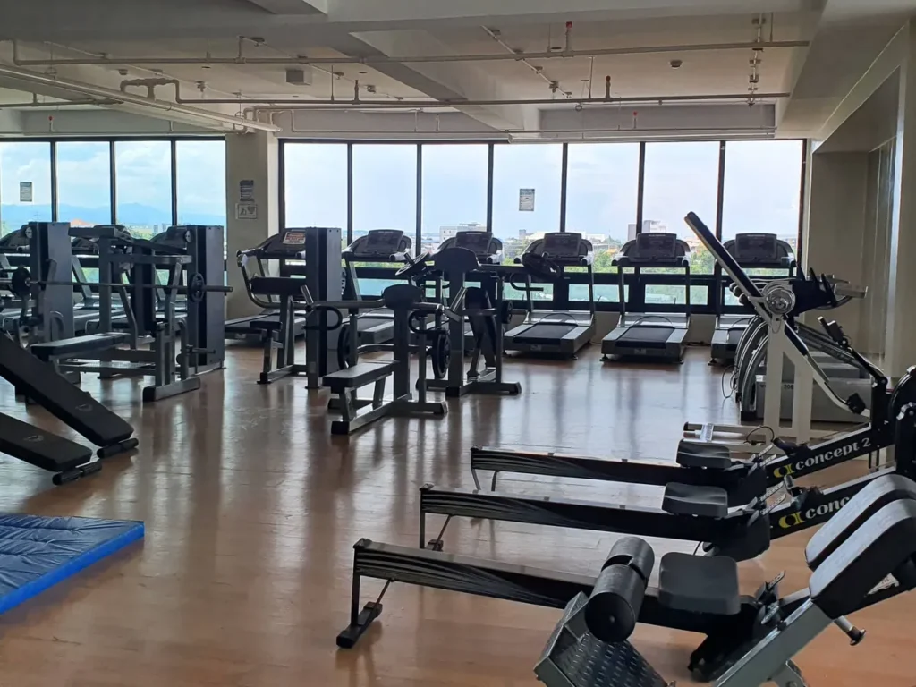 필리핀 세부 CIA어학원 헬스장 전경으로 통창 너머 도심 풍경과 함께 러닝머신, 로잉머신, 웨이트 기구가 넓게 배치돼 있다.