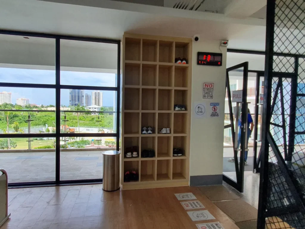 필리핀 세부 CIA어학원 헬스장 입구의 우드 신발장으로 칸마다 운동화가 놓이고 노 스트리트 슈즈 안내문이 붙어 있다.