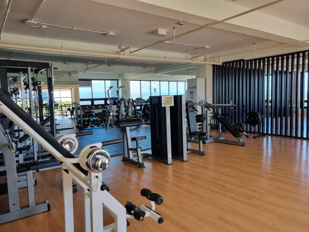 필리핀 세부 CIA어학원 헬스장으로 거울 벽 앞에 케이블 머신과 덤벨 랙이 놓이고 우드 바닥 공간이 이어진다.