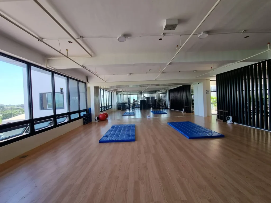 필리핀 세부 CIA어학원 헬스장 한편으로 우드 바닥 위에 인피니티 머신과 어시스트 풀업 기구가 놓여 있다.
