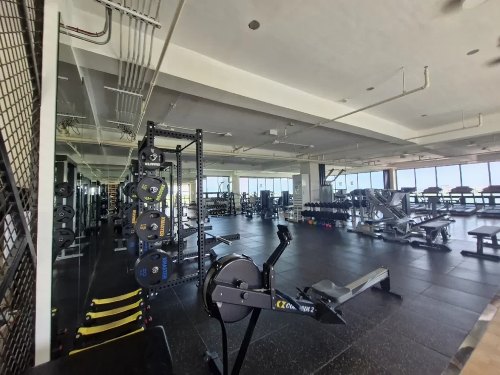 필리핀 세부 CIA어학원 헬스장으로 어두운 톤 바닥 위에 파워랙과 로잉머신, 다양한 웨이트 기구가 넓게 펼쳐져 있다.