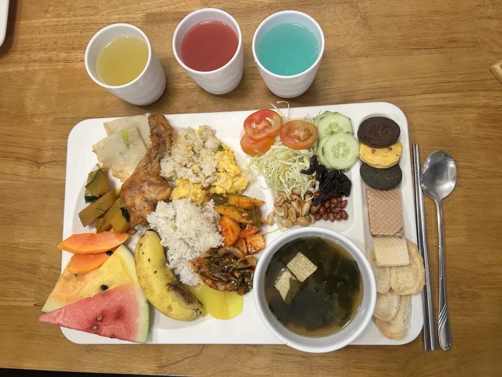 필리핀 세부 CIA어학원 식당 흰 식판에 밥, 닭고기, 채소볶음, 과일, 미역국과 음료 세 컵을 곁들인 한 끼