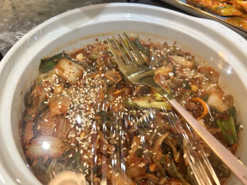 필리핀 세부 CIA어학원 식당 흰 옹기 그릇에 깨를 뿌려 버무린 배추김치를 포크 두 개와 함께 담은 모습