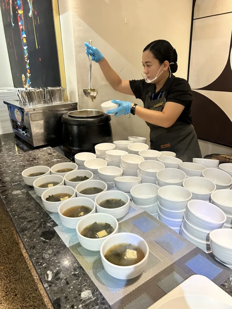 필리핀 세부 CIA어학원 식당 직원이 검은 옹기솥의 미역국을 떠 여러 흰 그릇에 나눠 담는 배식 모습