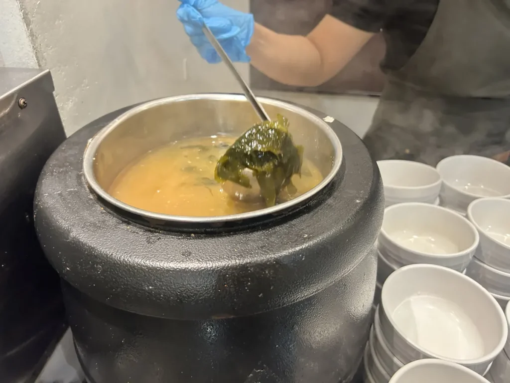 필리핀 세부 CIA어학원 식당 옹기솥에서 미역이 든 국을 국자로 뜨는 모습과 옆에 쌓인 빈 국그릇들