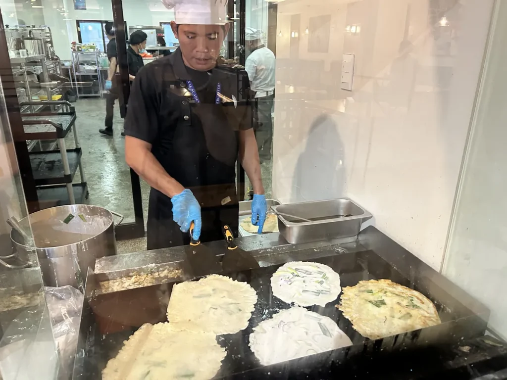 필리핀 세부 CIA어학원 식당 유리 너머로 조리사가 철판에서 쪽파 부침개를 부치는 라이브 조리 장면