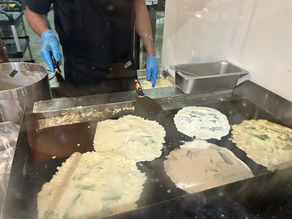 필리핀 세부 CIA어학원 식당 조리사가 철판 위에서 쪽파를 넣은 부침개 반죽 여러 장을 부치는 모습