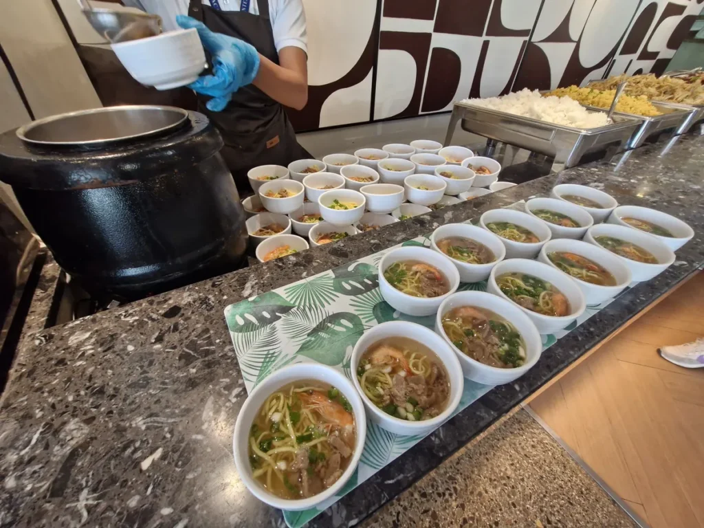 필리핀 세부 CIA어학원 식당 직원이 검은 옹기솥 국을 떠 1인용 그릇에 담아 나란히 준비하는 모습