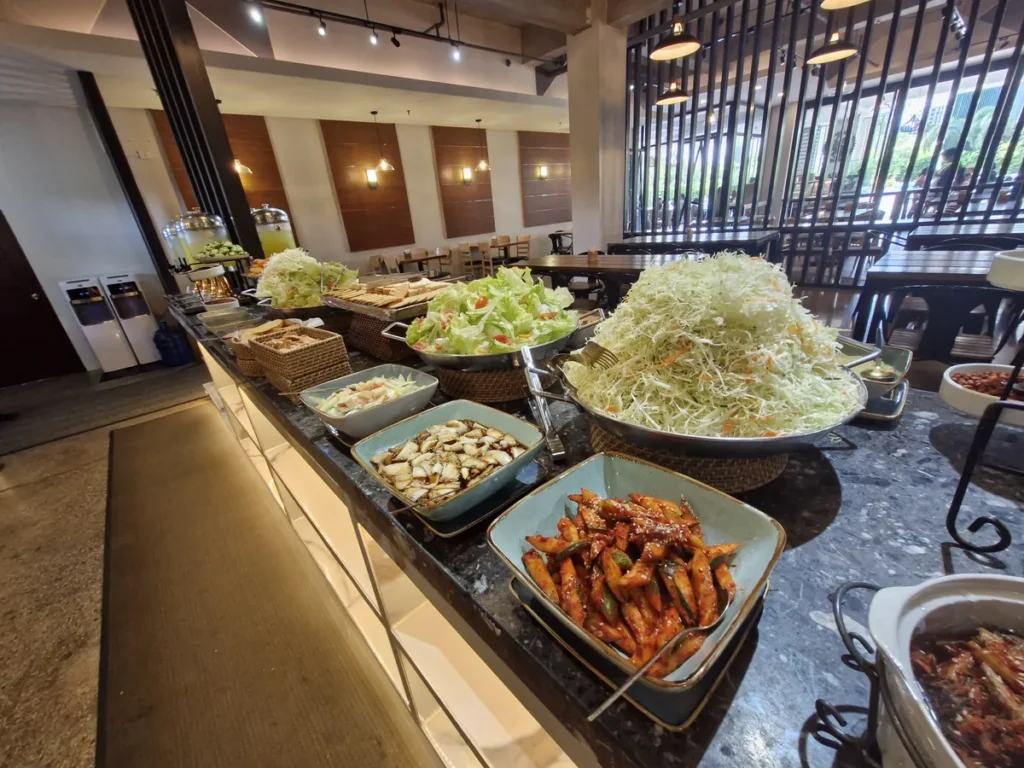 필리핀 세부 CIA어학원 식당 반찬대에 채 썬 양배추 샐러드와 매콤 볶음 반찬, 견과류를 늘어놓은 모습