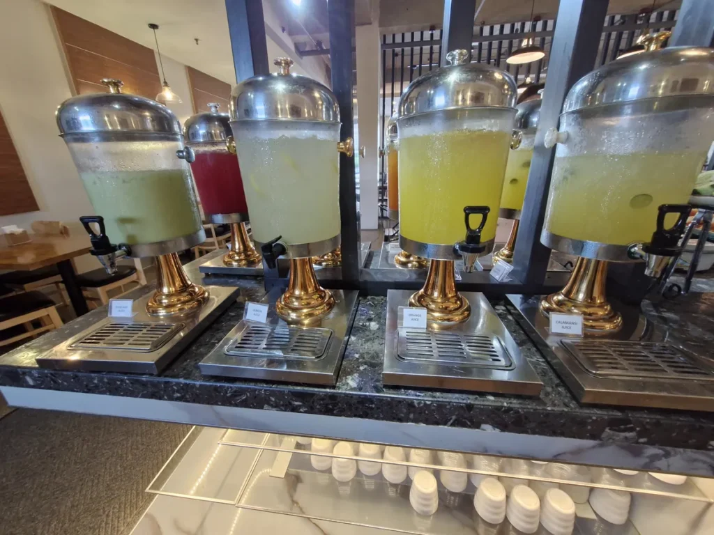 필리핀 세부 CIA어학원 식당 사탕수수·레몬·오렌지·칼라만시 주스 디스펜서가 라벨과 함께 줄지어 놓인 모습