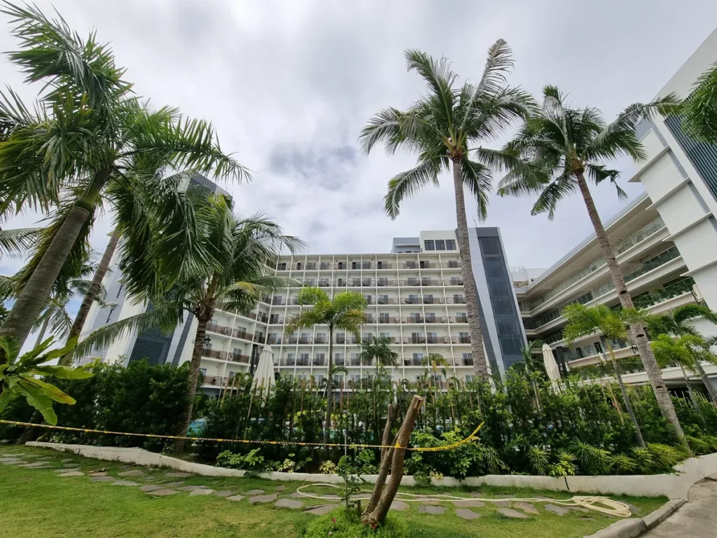 필리핀 세부 CIA어학원 본관, 키 큰 야자수 사이로 발코니가 보이는 리조트형 건물을 정원에서 올려다본 모습