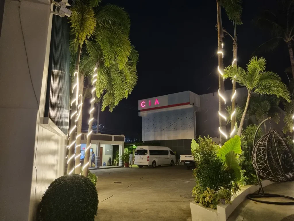 필리핀 세부 CIA어학원 야간 정문, 야자수에 두른 조명이 빛나고 CIA 네온 간판과 차량 진입로가 보이는 저녁 풍경