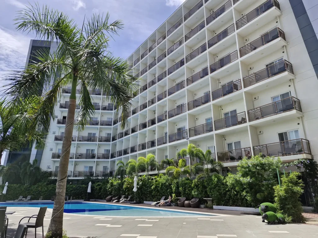 필리핀 세부 CIA어학원 정문 외관, CIA 간판과 점무늬 외벽 건물 앞에 차량이 주차되고 옆에 idp 건물이 보이는 낮 풍경