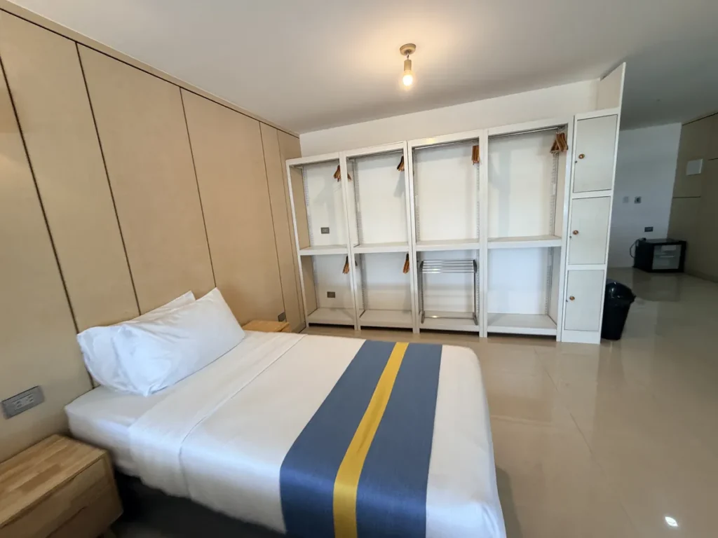 필리핀 세부 SMEAG엔칸토 기숙사 객실 침대와 오픈 옷장 선반