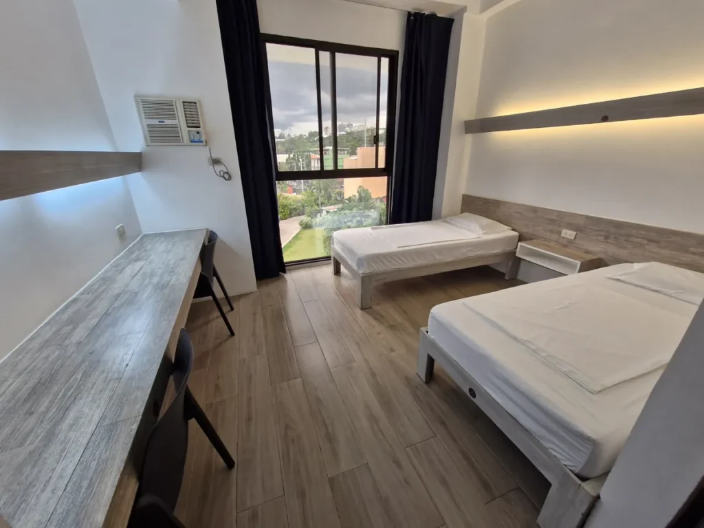 필리핀 세부 EV어학원 2인실 침대 두 개와 책상 통창