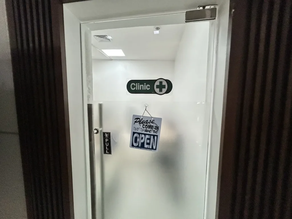 필리핀 막탄 QQ어학원 Clinic OPEN 표지가 걸린 의무실 입구 유리문