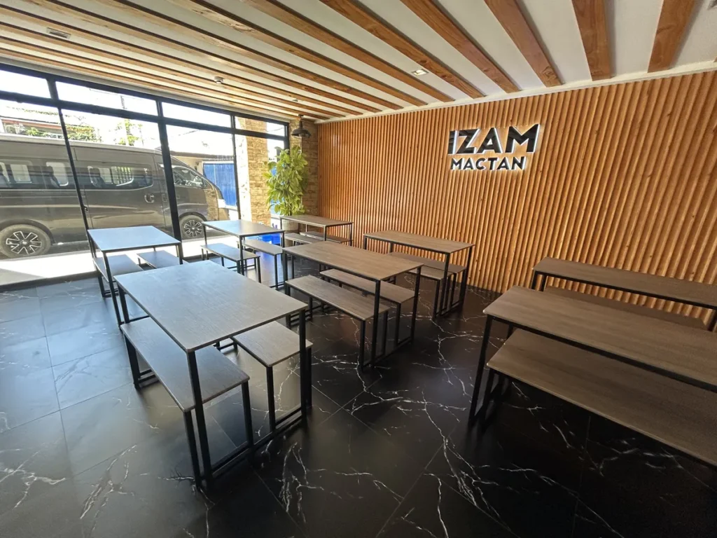 필리핀 막탄 IZAM어학원 IZAM 로고 벽과 나무 책상이 있는 식당