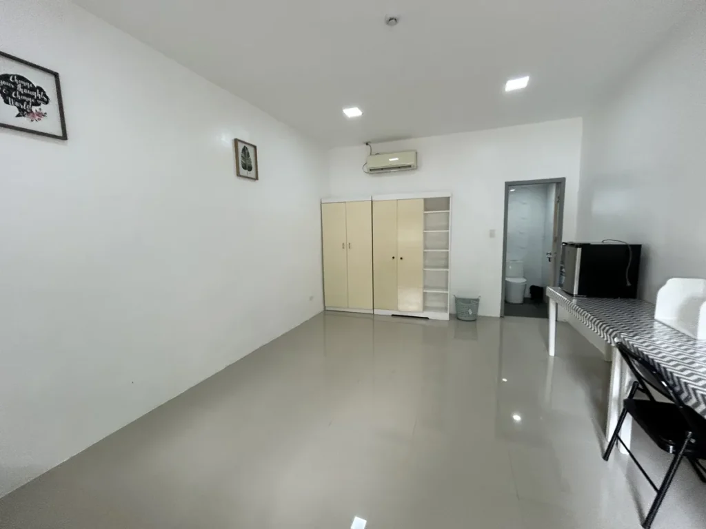 필리핀 클락 벨라(BELA) 어학원 기숙사 1인실로, 크림색 옷장 옆 화장실 문이 열려 있고 미니냉장고와 접이식 의자가 놓인 방 모습입니다.
