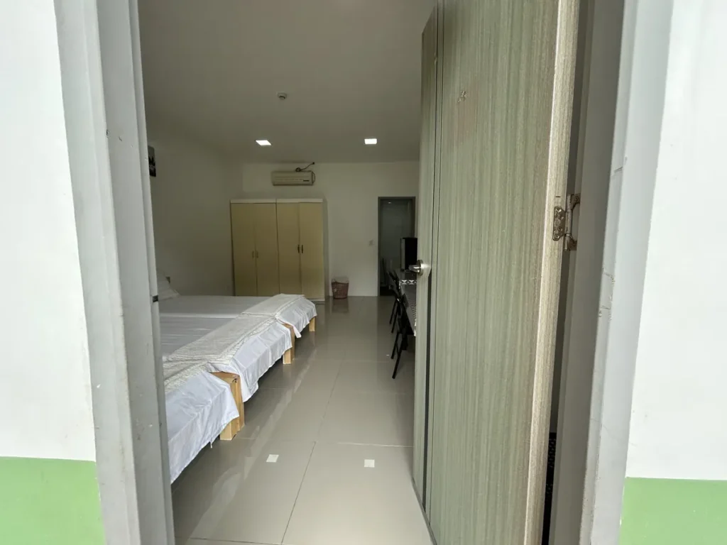 필리핀 클락 벨라(BELA) 어학원 기숙사 3인실로, 열린 문 너머 침대와 옷장, 에어컨, 안쪽 테이블·의자까지 보이는 객실 입구 전경입니다.