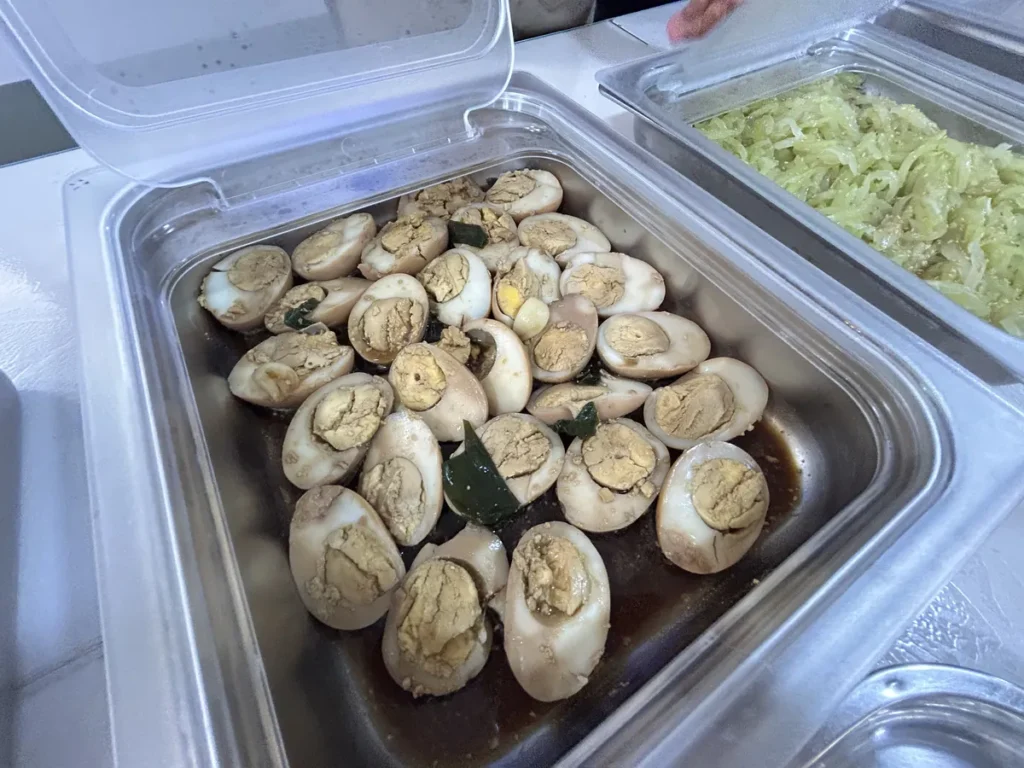 필리핀 클락 벨라(BELA) 어학원 식당 식사로, 배식통에 반으로 자른 삶은 계란이 간장 양념에 조려진 채 담겨 있습니다.